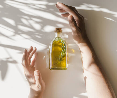 sunlight-falling-hands-covering-oil-bottle-white-background